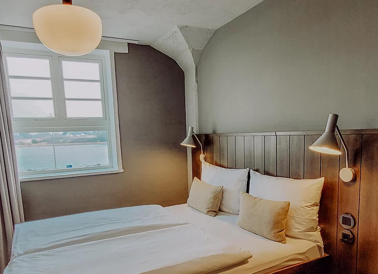 Gemütliches Schlafzimmer mit geschmackvoller Wandbeleuchtung und Blick auf das Meer