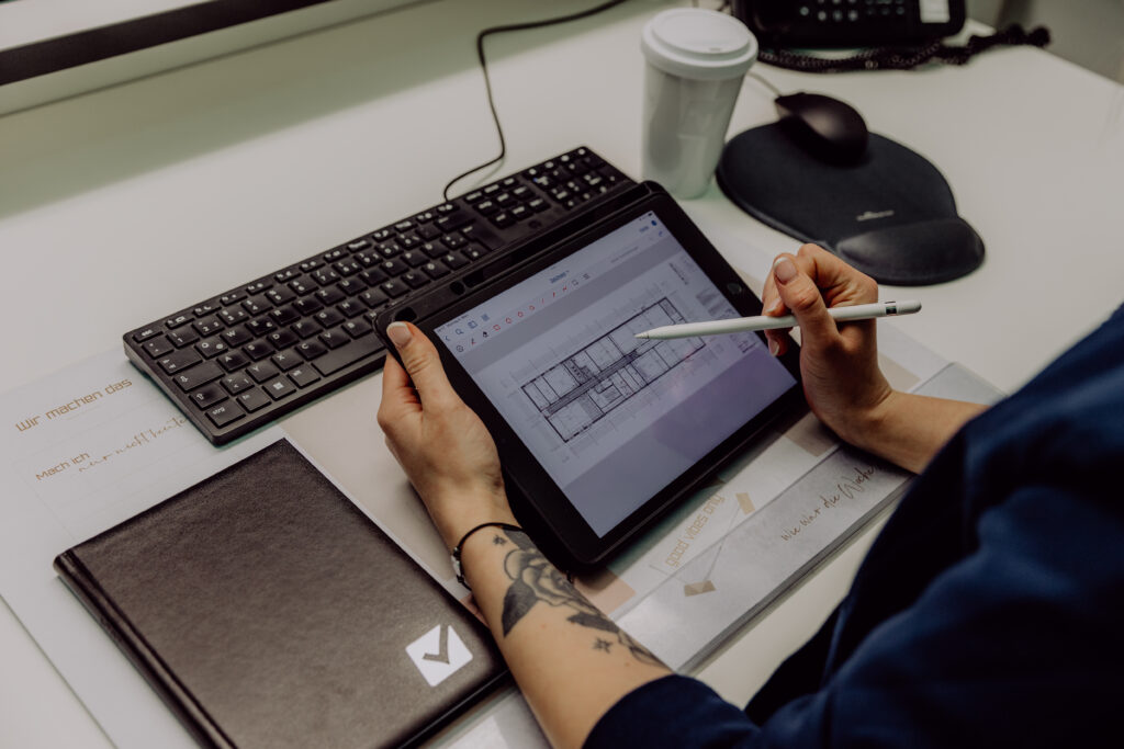 Arbeitsplatz mit Tablet und Bauplanzeichnung bei Nickels Anstriche