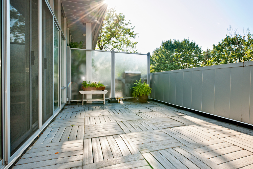 Ein gemütlicher Balkon mit Holzfliesen und Pflanzen bietet einen einladenden Außenbereich zum Entspannen und Verweilen.